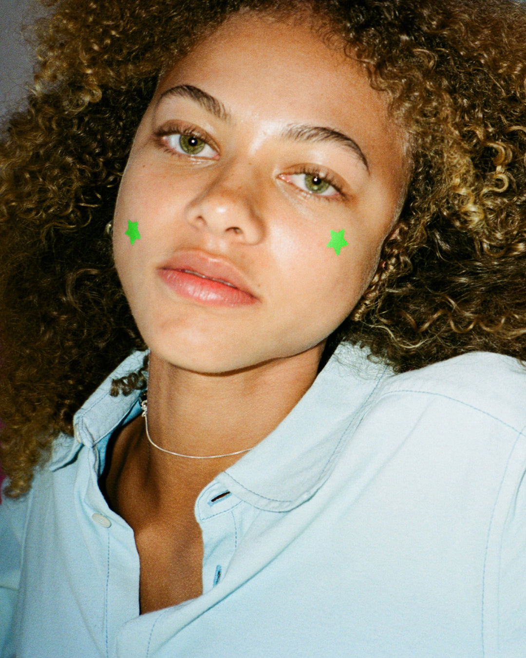 A person wearing green Starface Hydro-Star® + Tea Tree patches. Star-shaped patches that soothe spots.