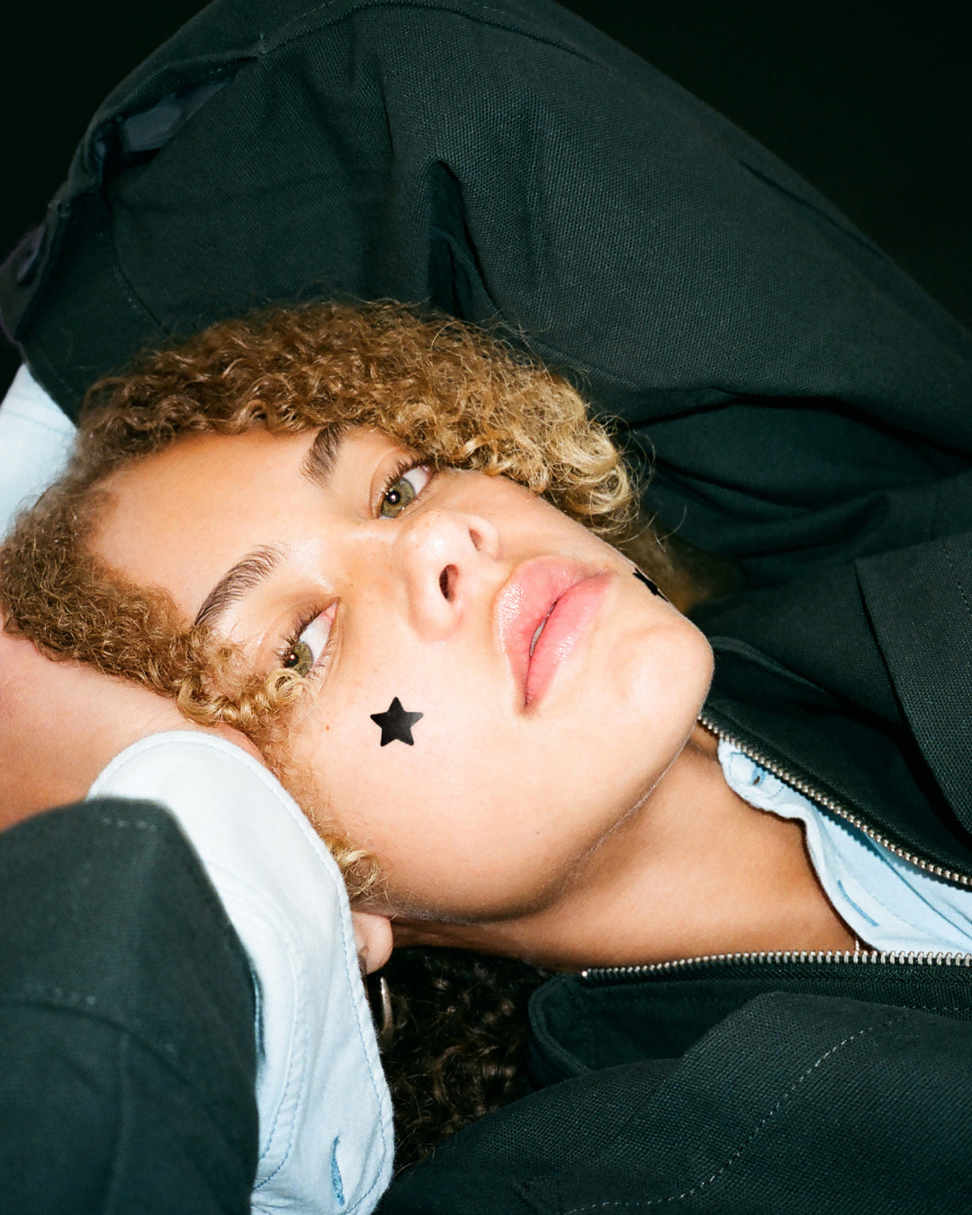 Closeup of black Starface Hydro-Star® star-shaped pimple patches on a spot. Hydrocolloid patches that shrink pimples.