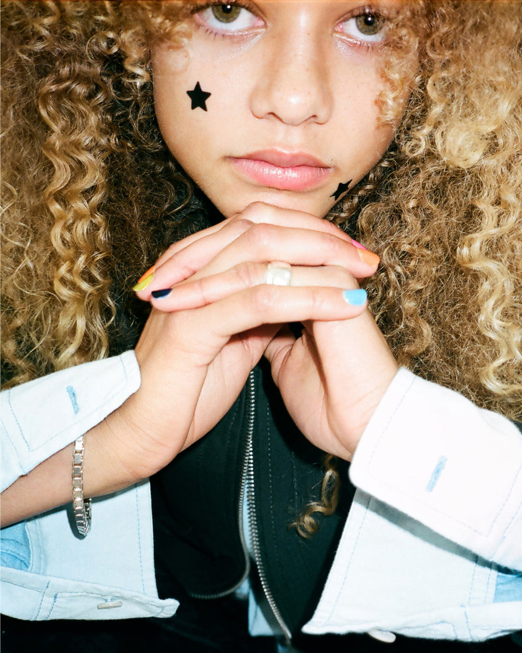 A person wearing black Starface Hydro-Star® pimple patches on their face. Star-shaped patches that shield each spot.