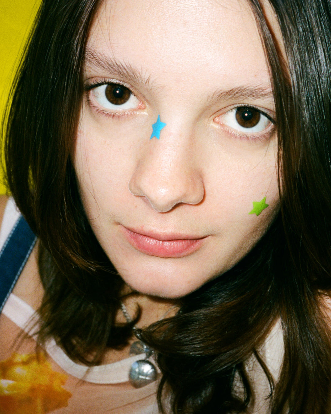 Closeup of bright Starface Hydro-Star® star-shaped pimple patches on a spot. Hydrocolloid patches that shrink pimples.