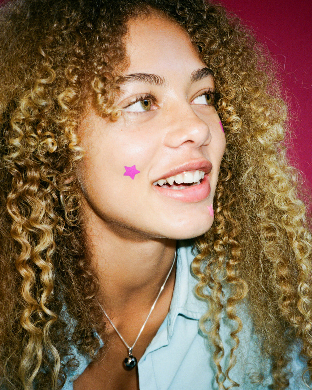 A person wearing pink Starface Hydro-Star® star-shaped pimple patches.
