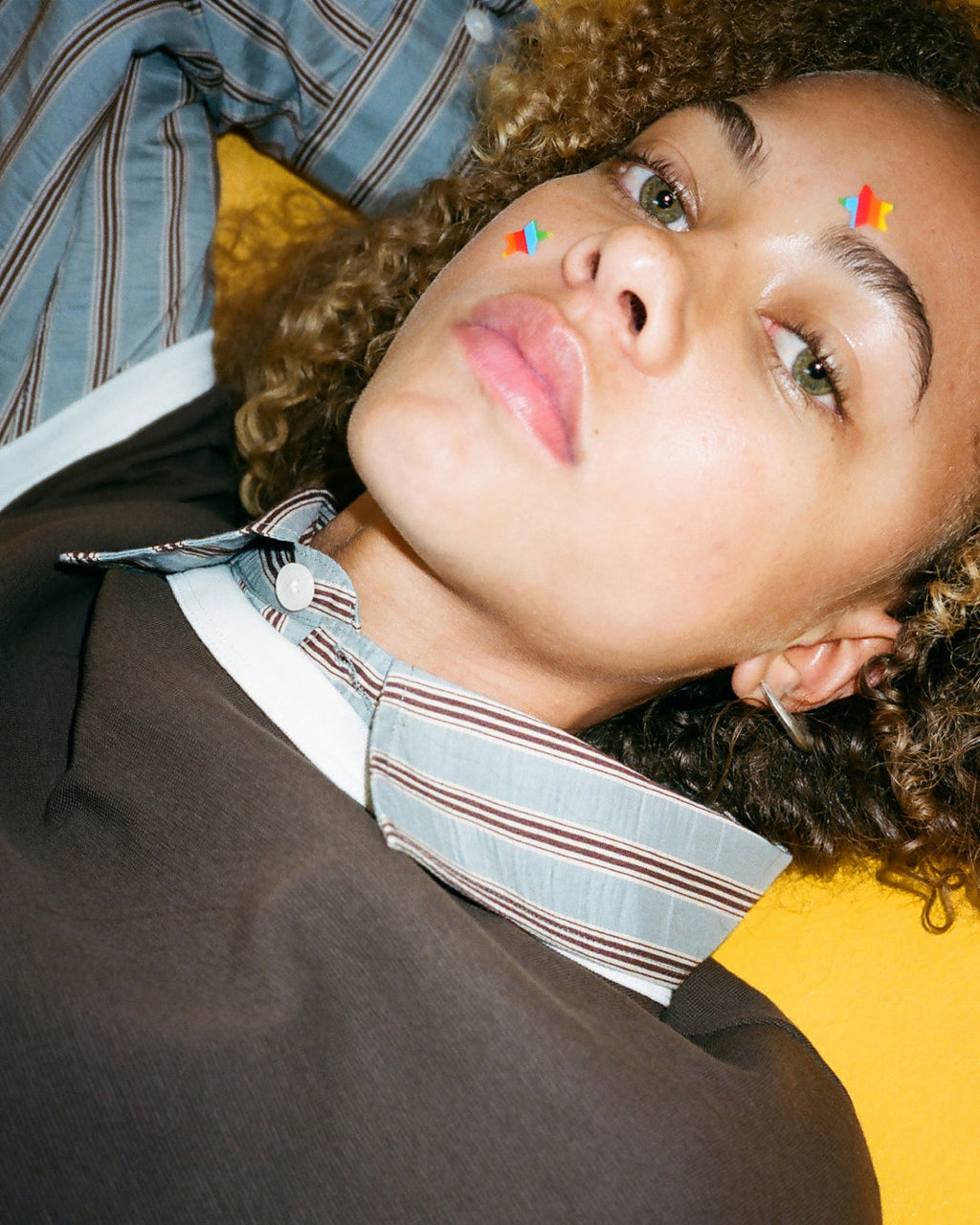 Closeup of rainbow Starface Hydro-Star® star-shaped pimple patches on a spot. Hydrocolloid patches that shrink pimples.