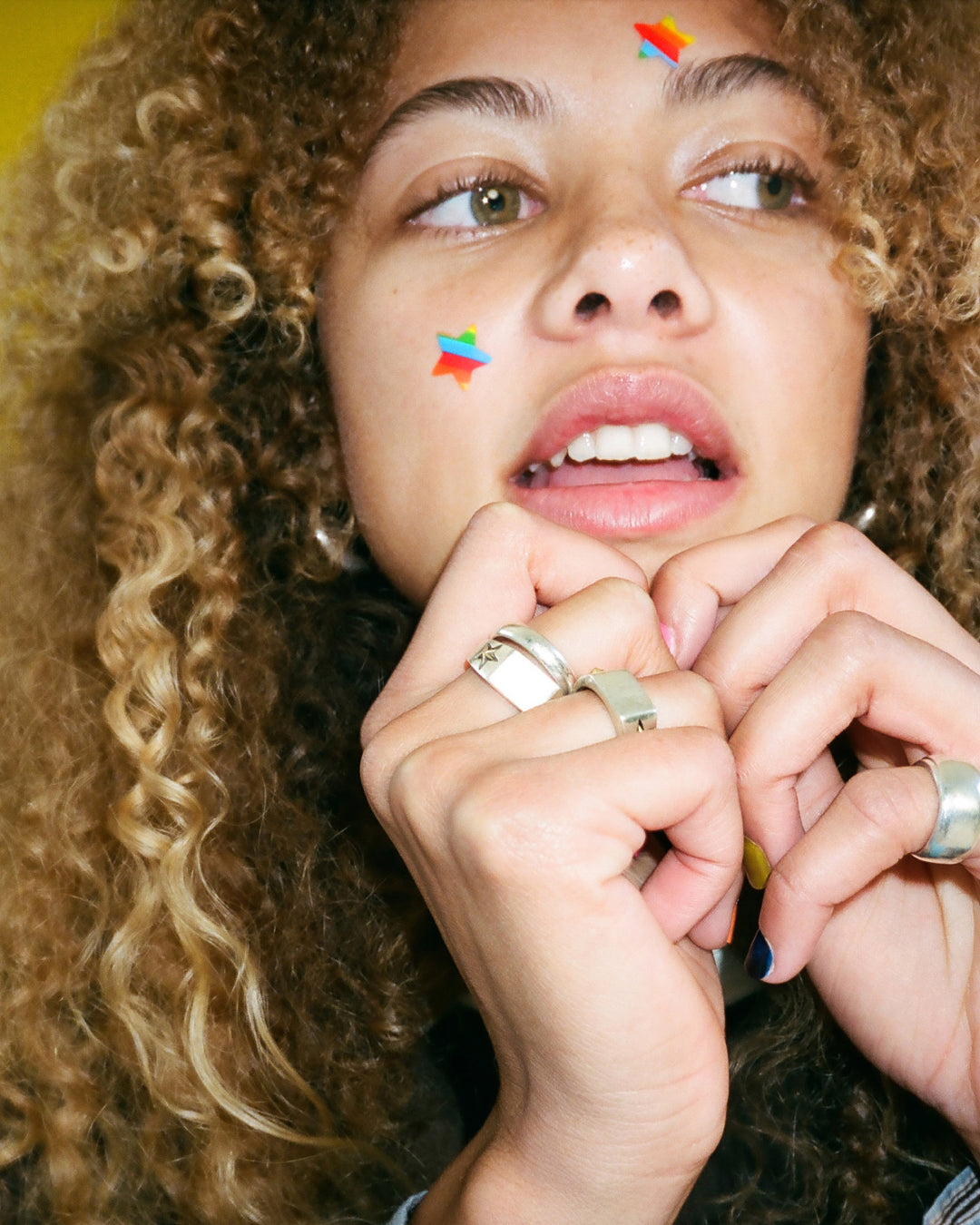 A person wearing rainbow Starface Hydro-Star® pimple patches on their face. Star-shaped patches that shield each spot.