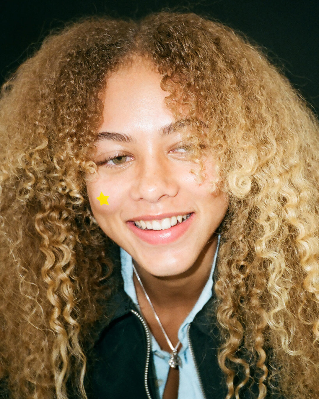 Lifestyle portrait of a person with yellow Starface Hydro-Star® patches. Classic star-shaped pimple patches.