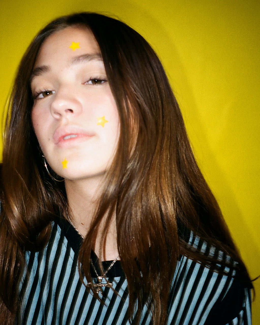 A person wearing yellow Starface Hydro-Star® pimple patches on their face. Star-shaped patches that shield each spot.