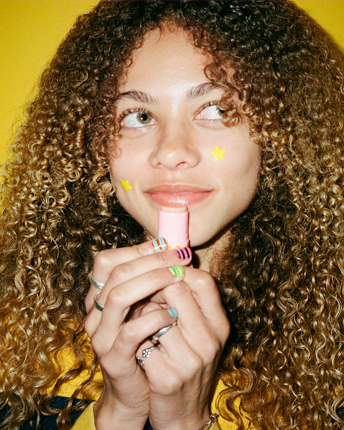 Lifestyle portrait of a person with Starface Star Balm® Perfectly Peachy. A limited-edition peach lip balm for daily wear.