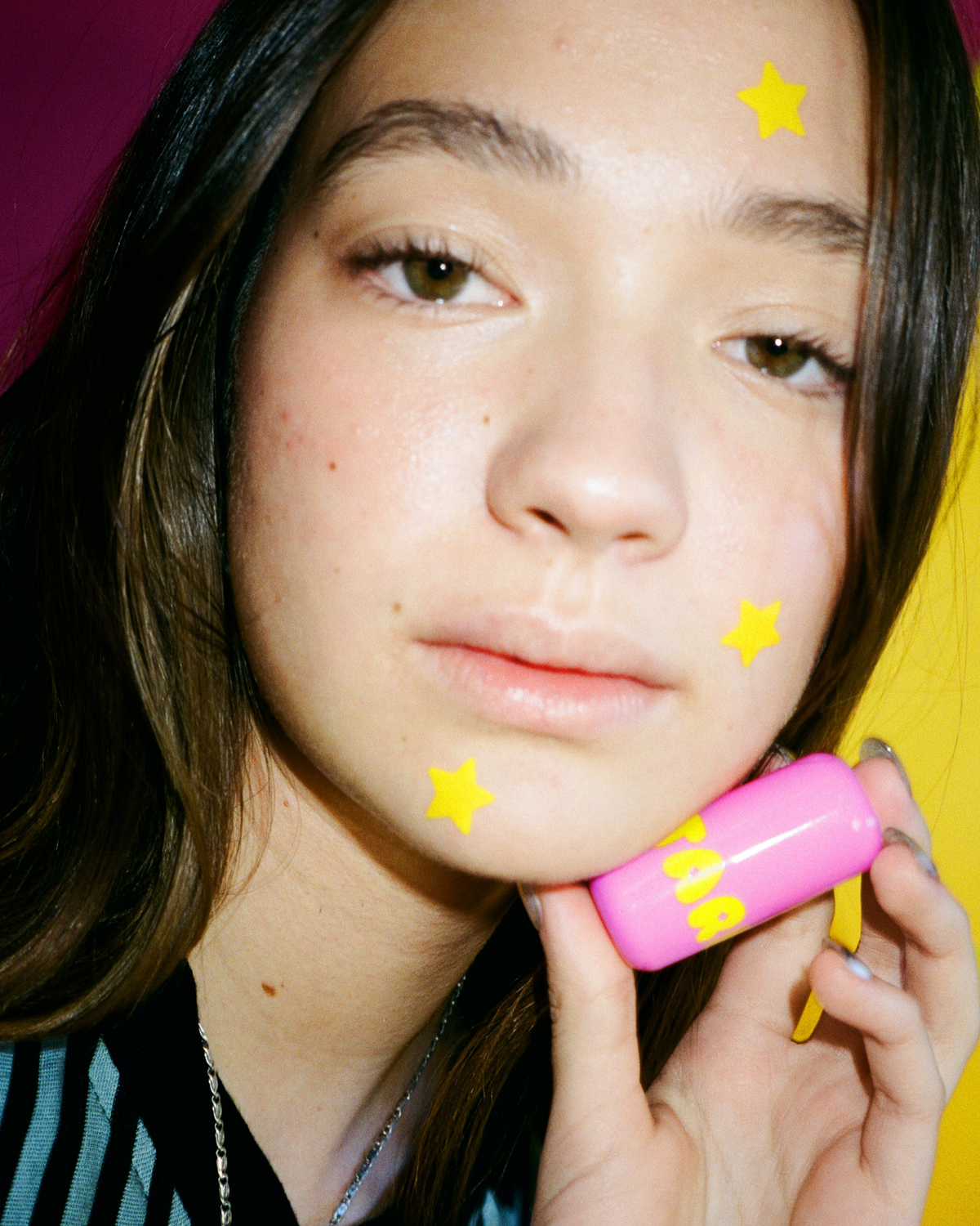A person holding Starface Star Balm® Starfruit from the Super Cute Trio. A tropical, cushiony lip balm.