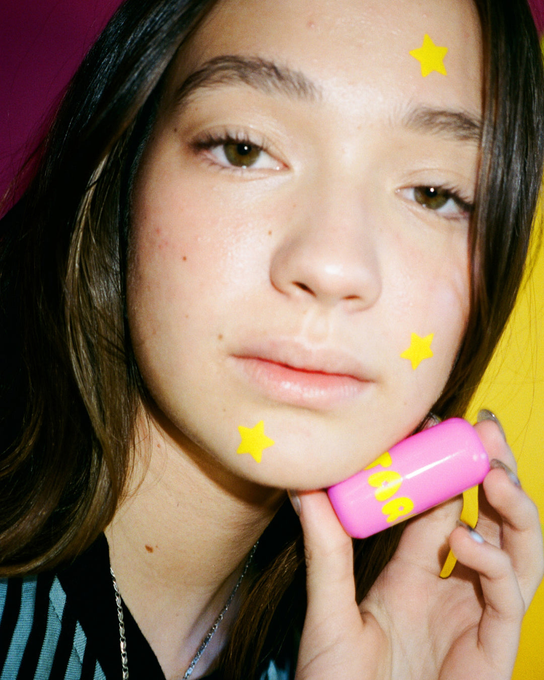 A person holding Starface Star Balm® from the Star Balm® Bundle. Moisturizing lip balms in four delish flavors.