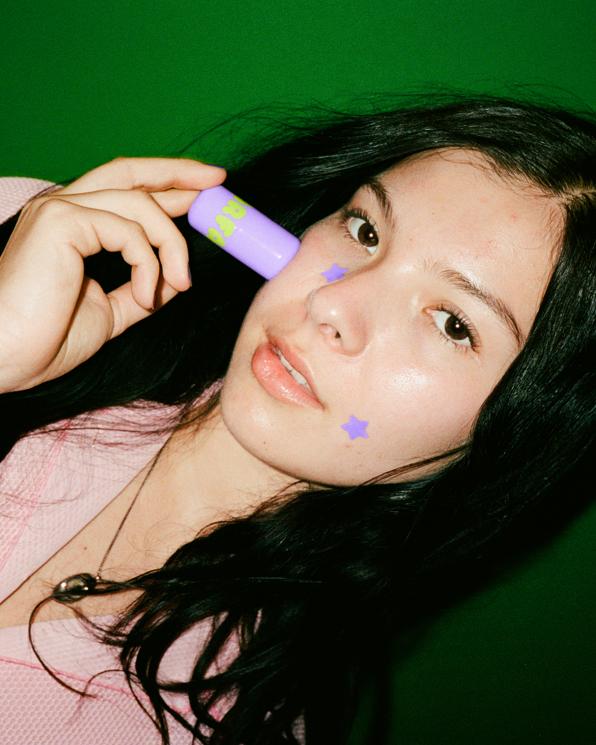 A person holds up Starface Star Balm® in Super Grape. This bright, fizzy grape lip balm leaves lips hydrated.
