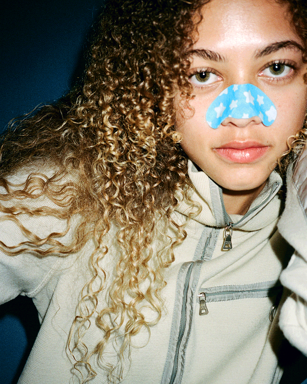A person wearing a blue Starface Star Strips™ + Salicylic Acid pore strip on their nose. Pore strips that lift away buildup.